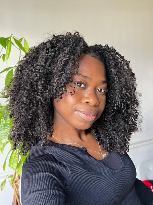 A person wearing a kinky curly u-part wig with a natural leave-out.